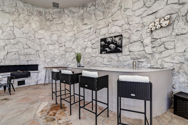 bar featuring stone finish floor and visible vents