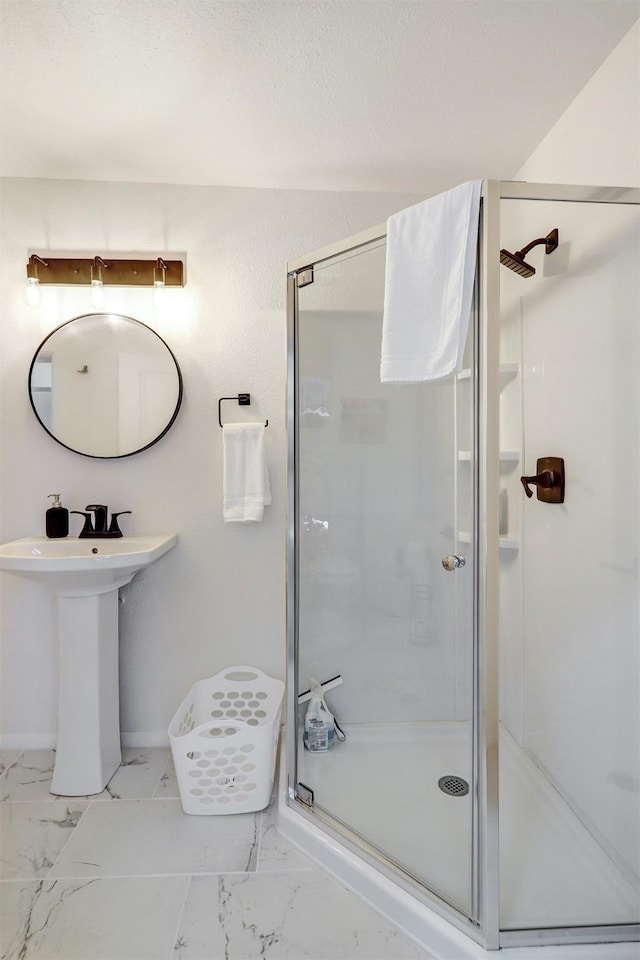 full bath featuring a sink, marble finish floor, and a stall shower