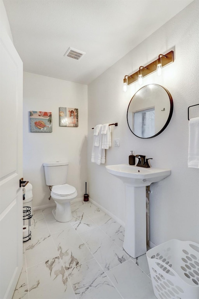 half bathroom with toilet, visible vents, marble finish floor, and baseboards