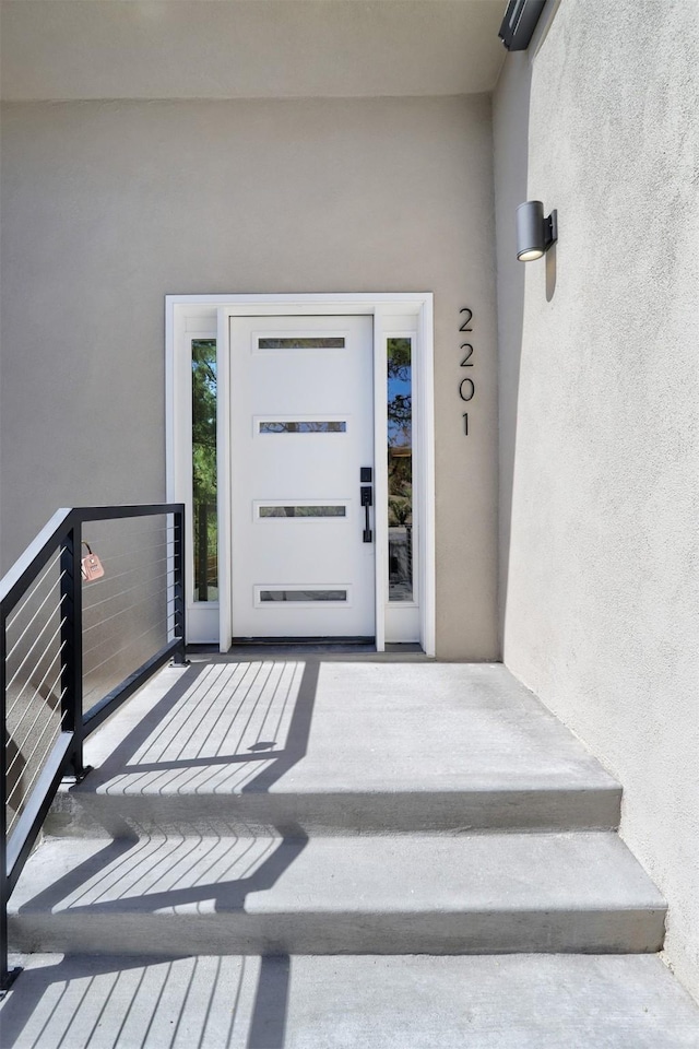 view of exterior entry with stucco siding and a balcony