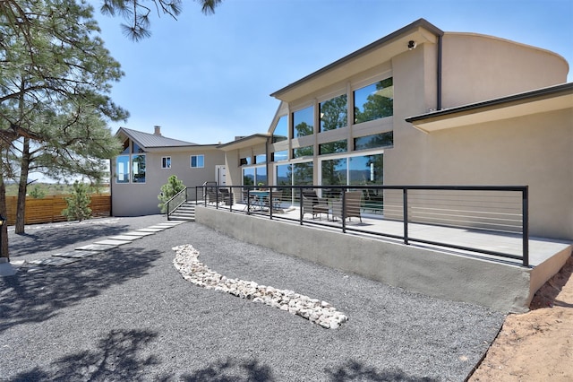 back of property with stucco siding, metal roof, a patio, and fence