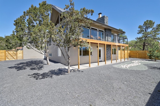 rear view of property featuring a patio, stucco siding, a fenced backyard, and a chimney