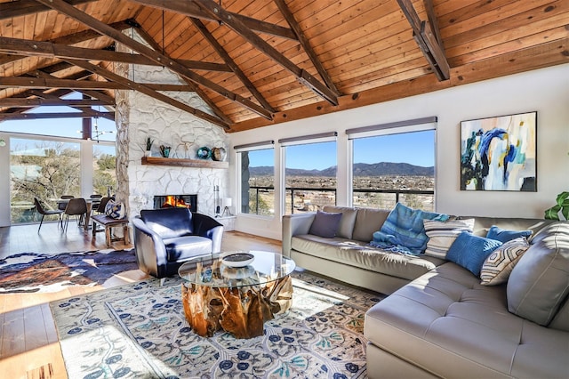 living room with wood ceiling, a mountain view, a stone fireplace, and hardwood / wood-style flooring