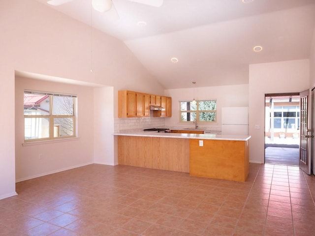 kitchen featuring a peninsula, a ceiling fan, freestanding refrigerator, and light countertops