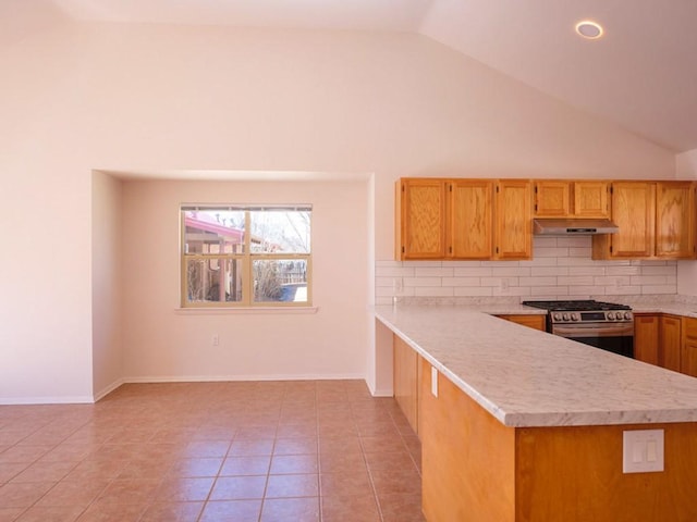 kitchen featuring light tile patterned floors, stainless steel gas range, light countertops, under cabinet range hood, and tasteful backsplash