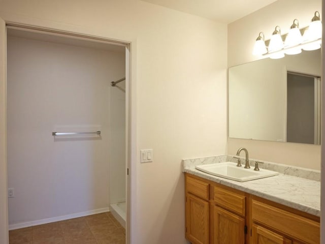 full bath with baseboards, tile patterned floors, vanity, and walk in shower