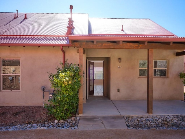 back of house with a patio area, metal roof, and stucco siding