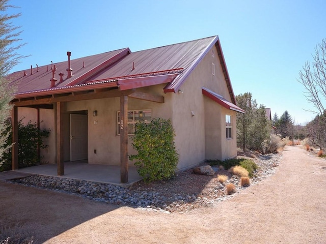 rear view of property with metal roof, a patio area, and stucco siding