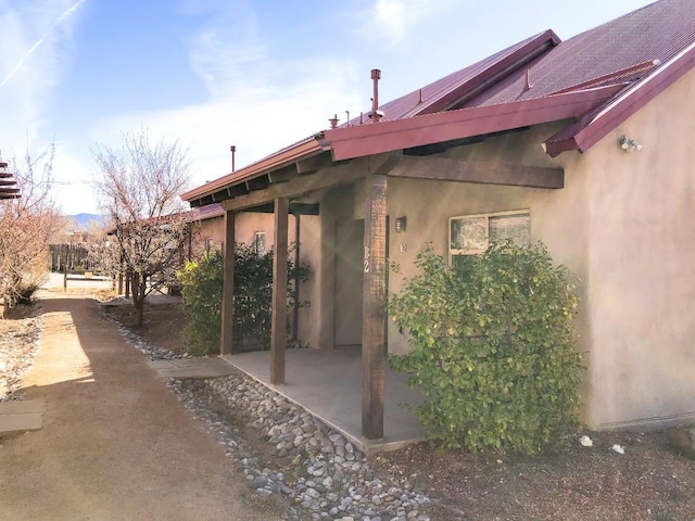 view of side of home featuring metal roof, a patio area, and stucco siding