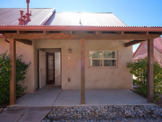 rear view of house featuring stucco siding and metal roof