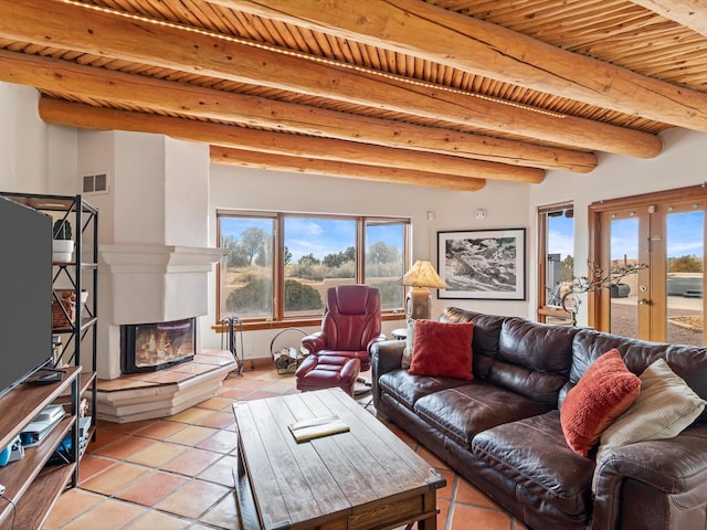 living area featuring beamed ceiling, visible vents, a glass covered fireplace, wooden ceiling, and light tile patterned floors