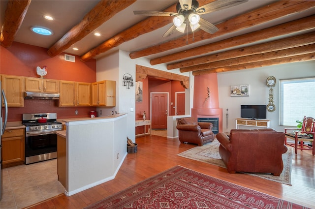 kitchen featuring visible vents, under cabinet range hood, open floor plan, light countertops, and gas range