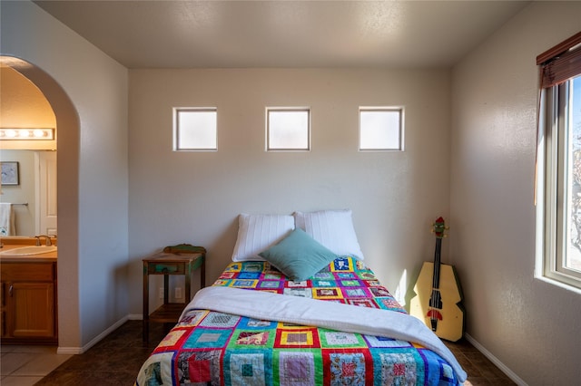 bedroom featuring baseboards, arched walkways, and tile patterned flooring