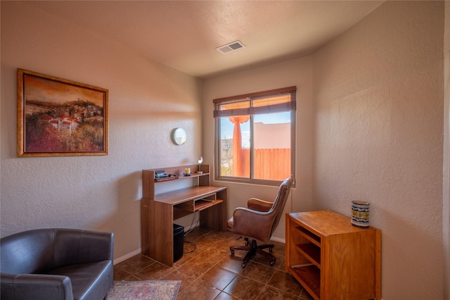 office space featuring tile patterned floors, baseboards, visible vents, and a textured wall