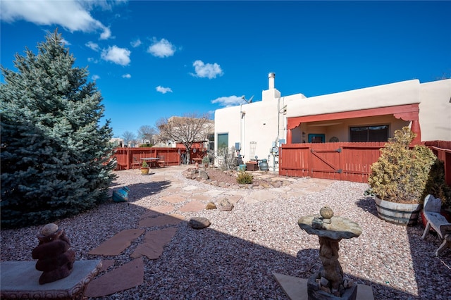 rear view of property featuring fence and a gate