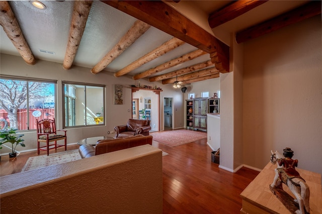 living area featuring beam ceiling, wood finished floors, visible vents, and baseboards