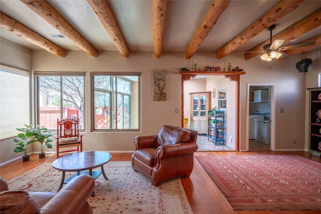 living area with wood finished floors, a ceiling fan, visible vents, and baseboards