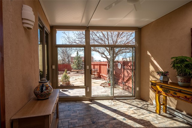 doorway featuring floor to ceiling windows, a textured wall, brick floor, and a wealth of natural light