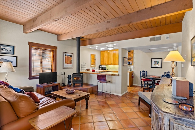 living room with visible vents, beam ceiling, light tile patterned flooring, wooden ceiling, and a wood stove