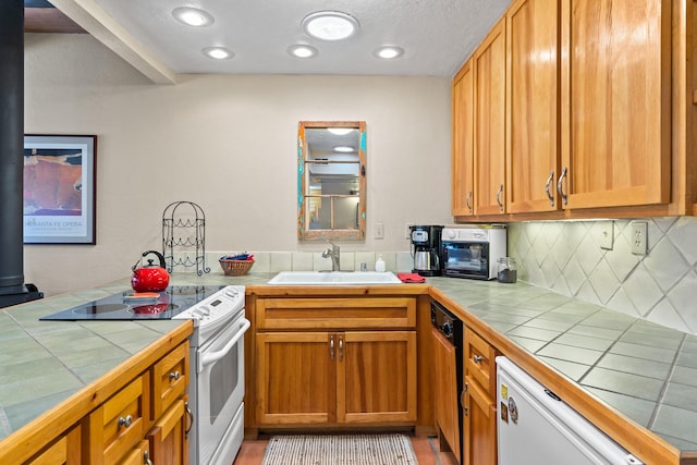 kitchen featuring a sink, white appliances, backsplash, and tile countertops