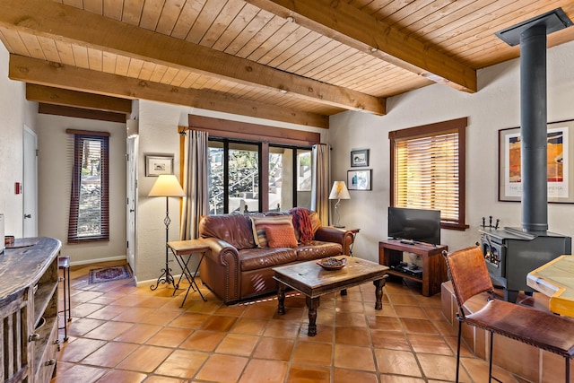 living room featuring light tile patterned flooring, beamed ceiling, wooden ceiling, and a wood stove