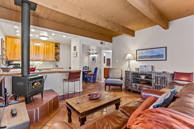 living area featuring light tile patterned floors, visible vents, a wood stove, wood ceiling, and beamed ceiling