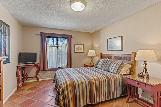 tiled bedroom with a textured ceiling and baseboards