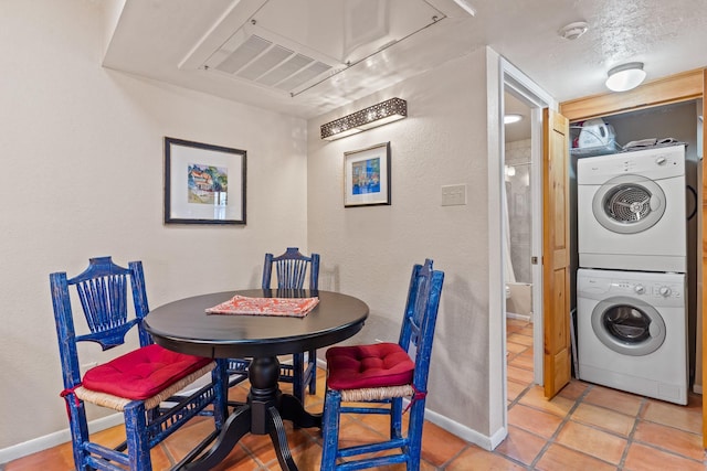 tiled dining area with stacked washer / dryer, attic access, a textured ceiling, and baseboards