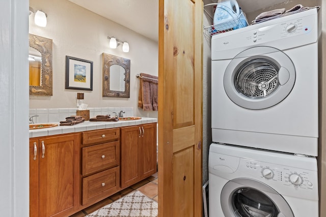 clothes washing area featuring a sink, stacked washer and clothes dryer, laundry area, and light tile patterned floors