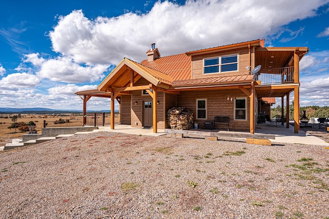 rear view of property with a balcony, a chimney, and a patio area