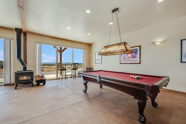 game room featuring billiards, a textured ceiling, finished concrete floors, recessed lighting, and a wood stove