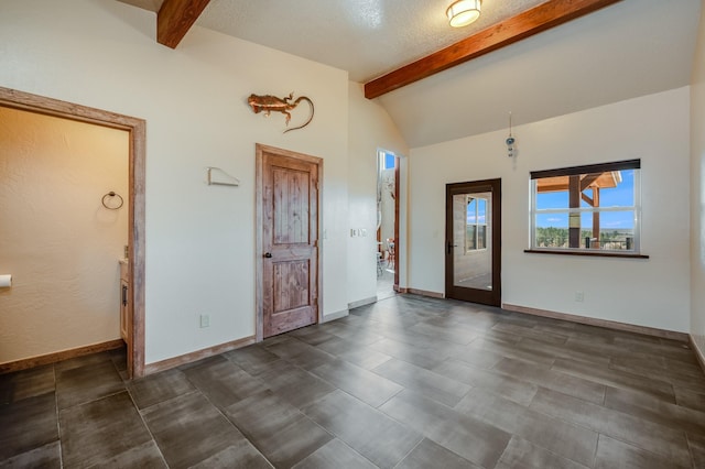 foyer entrance featuring lofted ceiling with beams and baseboards