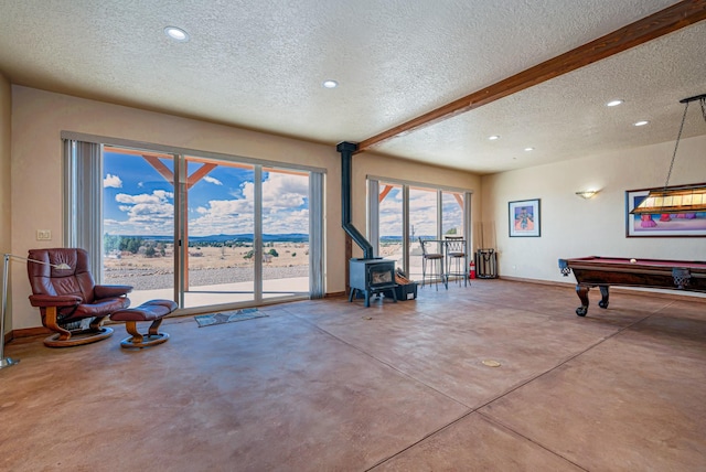 rec room featuring finished concrete flooring, baseboards, a wood stove, recessed lighting, and a textured ceiling