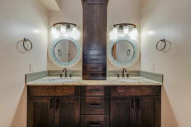 full bathroom featuring a sink, double vanity, and a textured wall