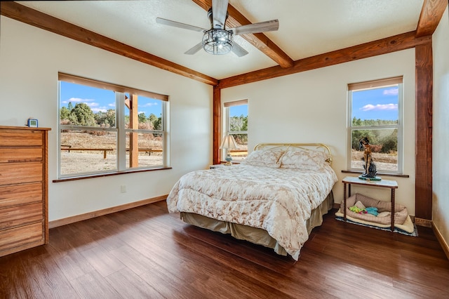 bedroom with dark wood-type flooring, beamed ceiling, multiple windows, and baseboards