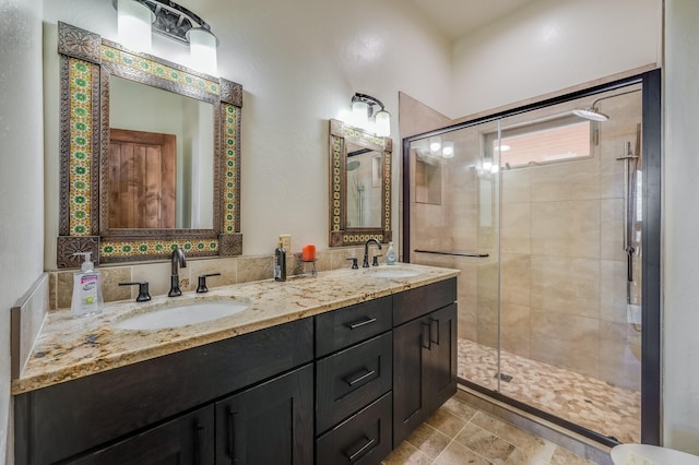 bathroom with double vanity, a shower stall, and a sink