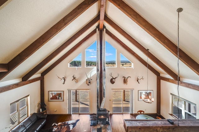 living room featuring beam ceiling, high vaulted ceiling, a wood stove, and wood finished floors