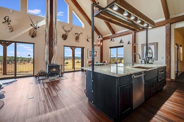 kitchen with beam ceiling, a wood stove, dark cabinets, and stainless steel appliances