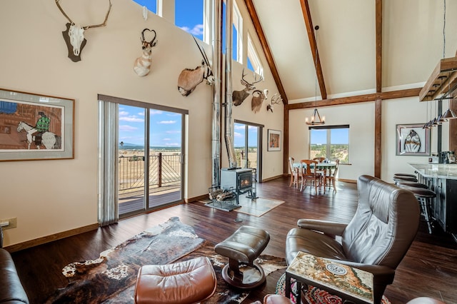 living room featuring beam ceiling, a wood stove, wood finished floors, and high vaulted ceiling