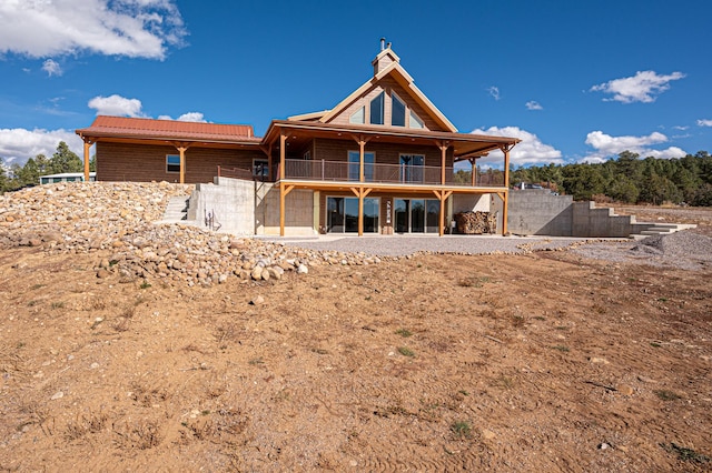 back of property featuring metal roof and a balcony