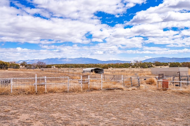 view of yard featuring a rural view, a mountain view, and fence