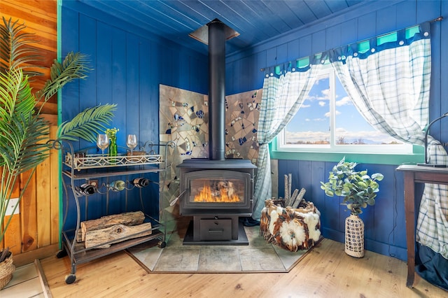 interior space featuring wooden ceiling, wooden walls, wood finished floors, and a wood stove