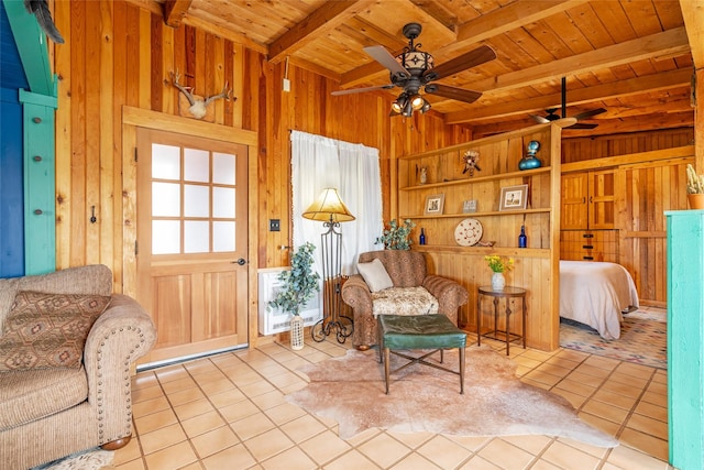 living area with wooden walls, vaulted ceiling with beams, ceiling fan, wood ceiling, and tile patterned floors