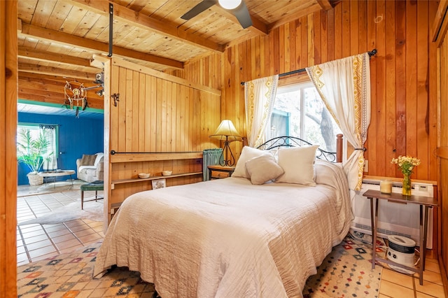 bedroom featuring beam ceiling, wooden walls, multiple windows, and light tile patterned flooring