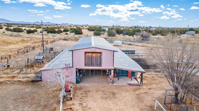 exterior space featuring a barn, a mountain view, an outdoor structure, and fence