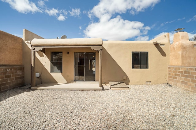 rear view of house with stucco siding and a patio