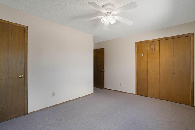 unfurnished bedroom with baseboards, light colored carpet, a closet, a textured ceiling, and a ceiling fan