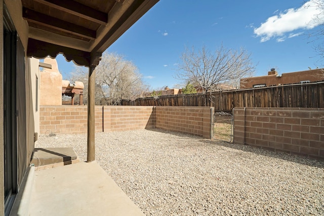 view of yard featuring a patio area, a fenced backyard, and a gate