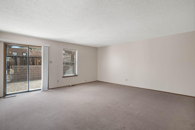 unfurnished room featuring carpet flooring, visible vents, and a textured ceiling