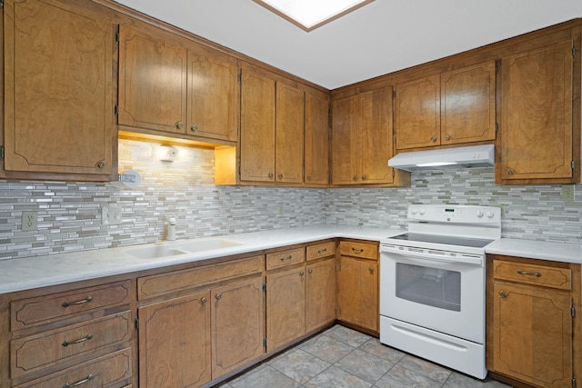 kitchen featuring under cabinet range hood, light countertops, decorative backsplash, white electric stove, and a sink